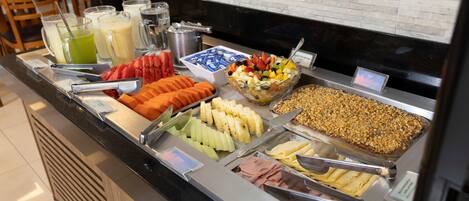 A buffet with various food options including fruits, vegetables, and meats.