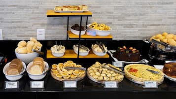 Un bufé con diversos alimentos, incluyendo pan, pasteles y una quiche.