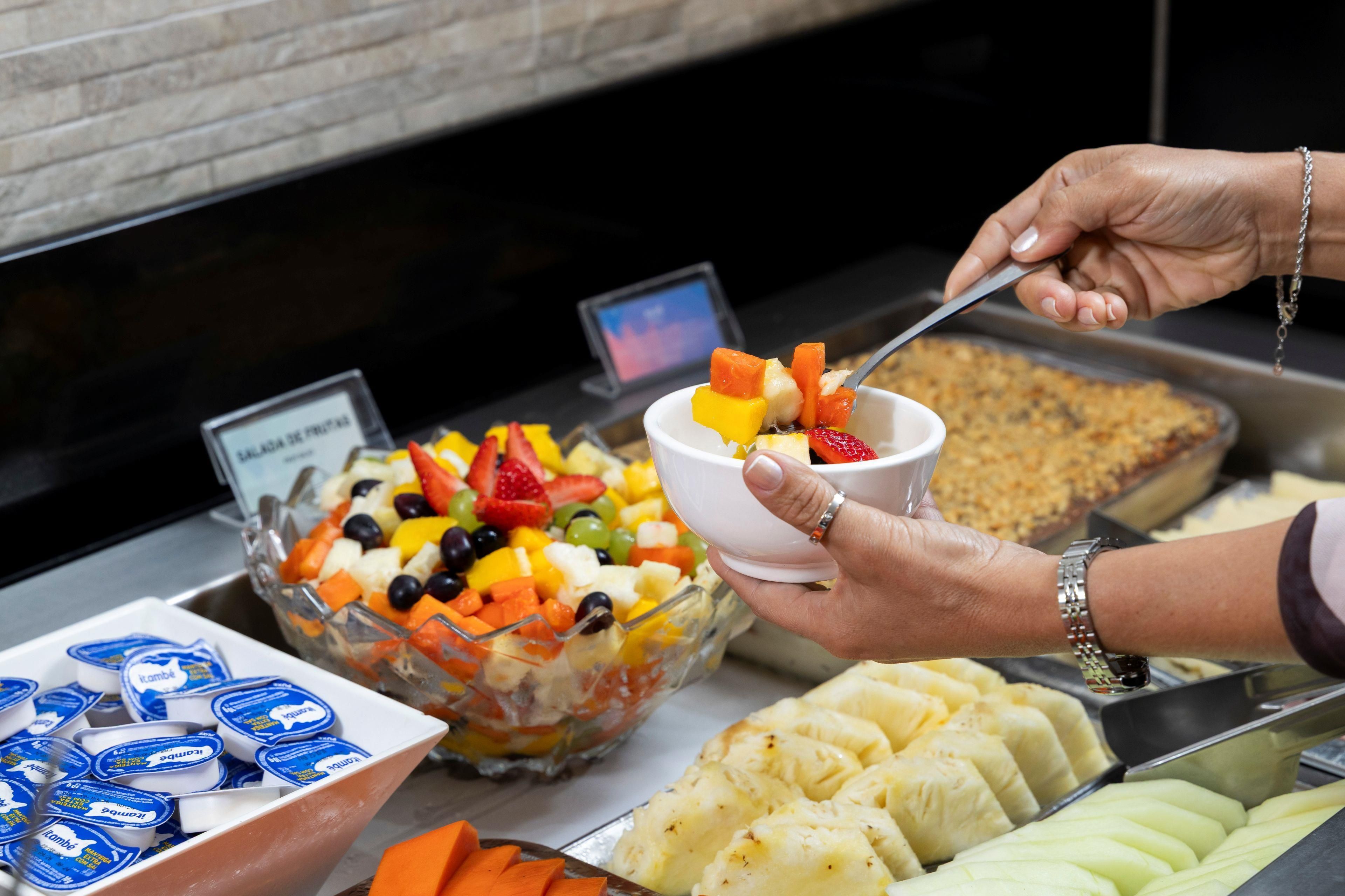 A buffet with a variety of food items including fruits, vegetables, and a bowl of yogurt.