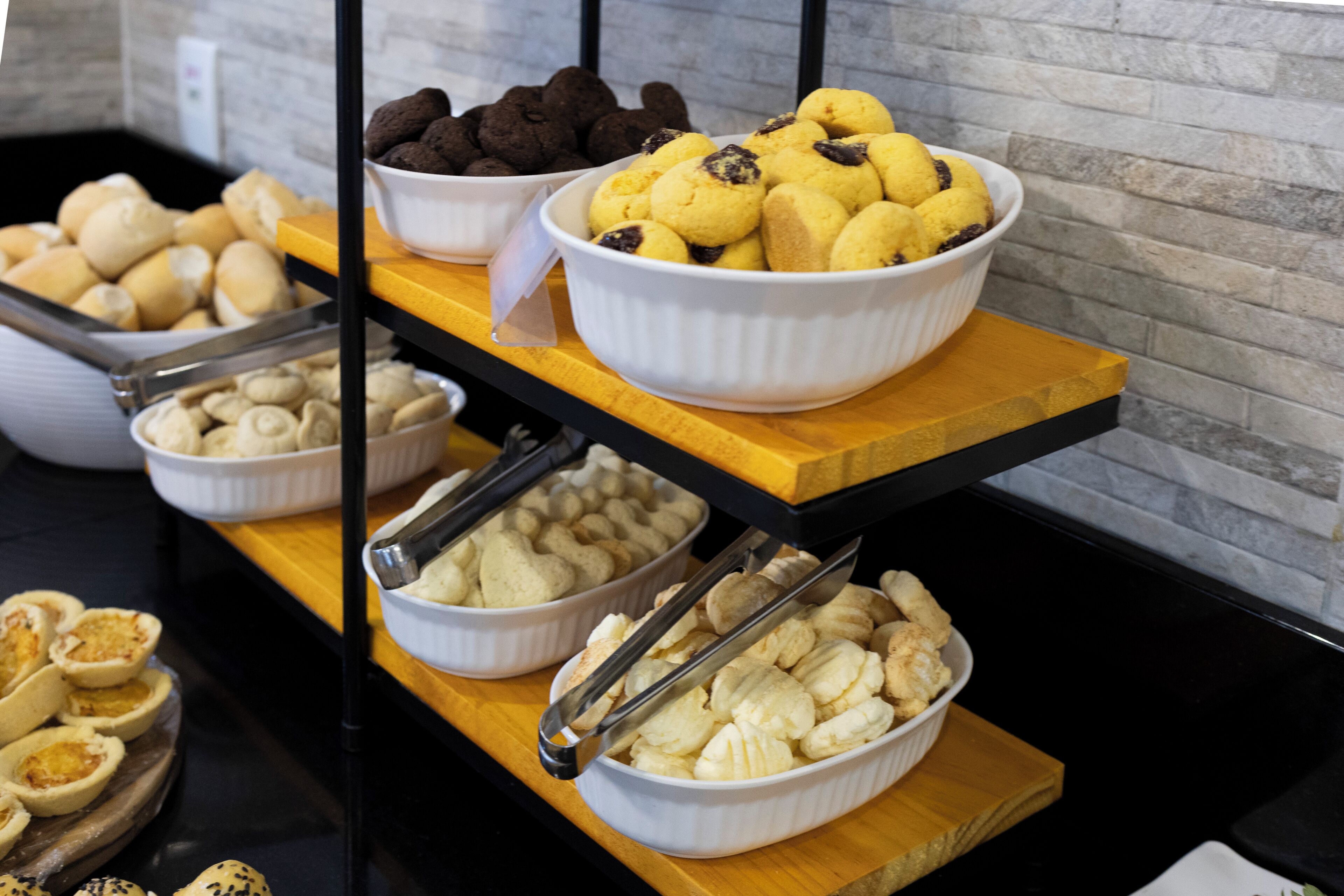 Un bufé con diversas opciones de panadería dispuestas en estantes de madera.