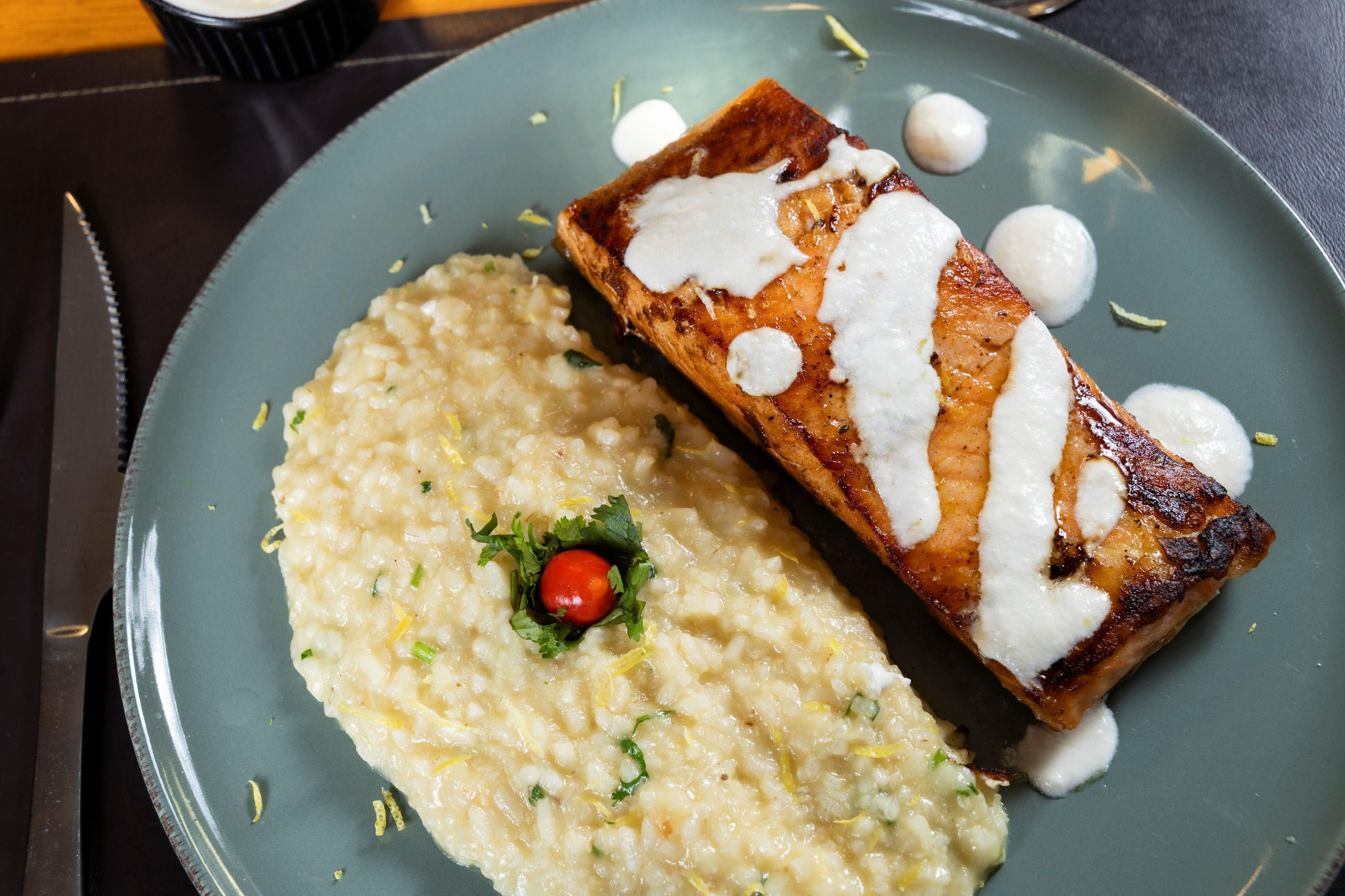 A plate with a piece of salmon and a side of risotto.