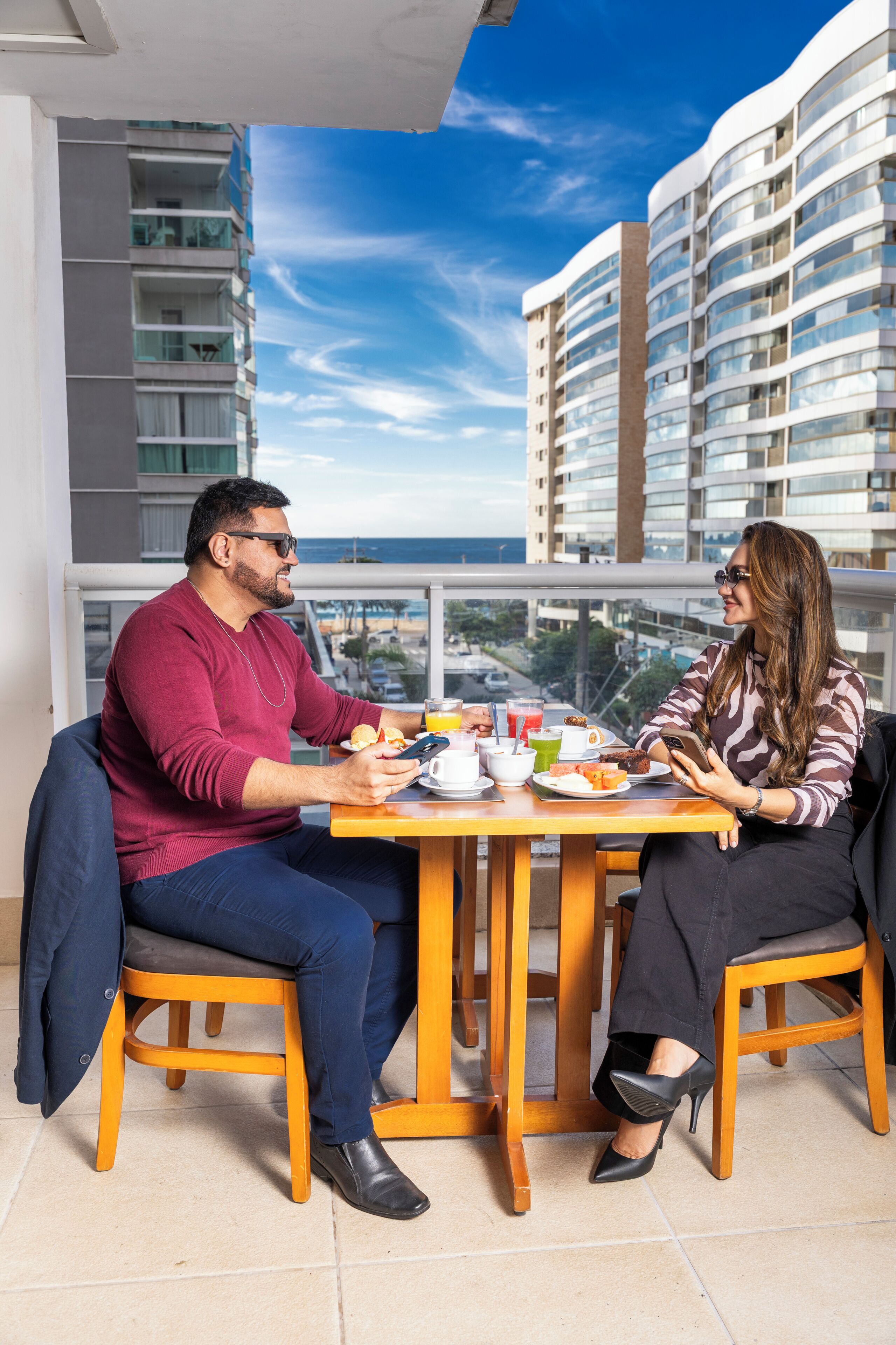 A dining area with a table set for two, overlooking a cityscape with high-rise buildings.