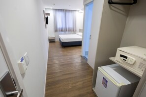 Habitació d'hotel amb un llit, una petita taula de nit, un microones i un frigorífic.