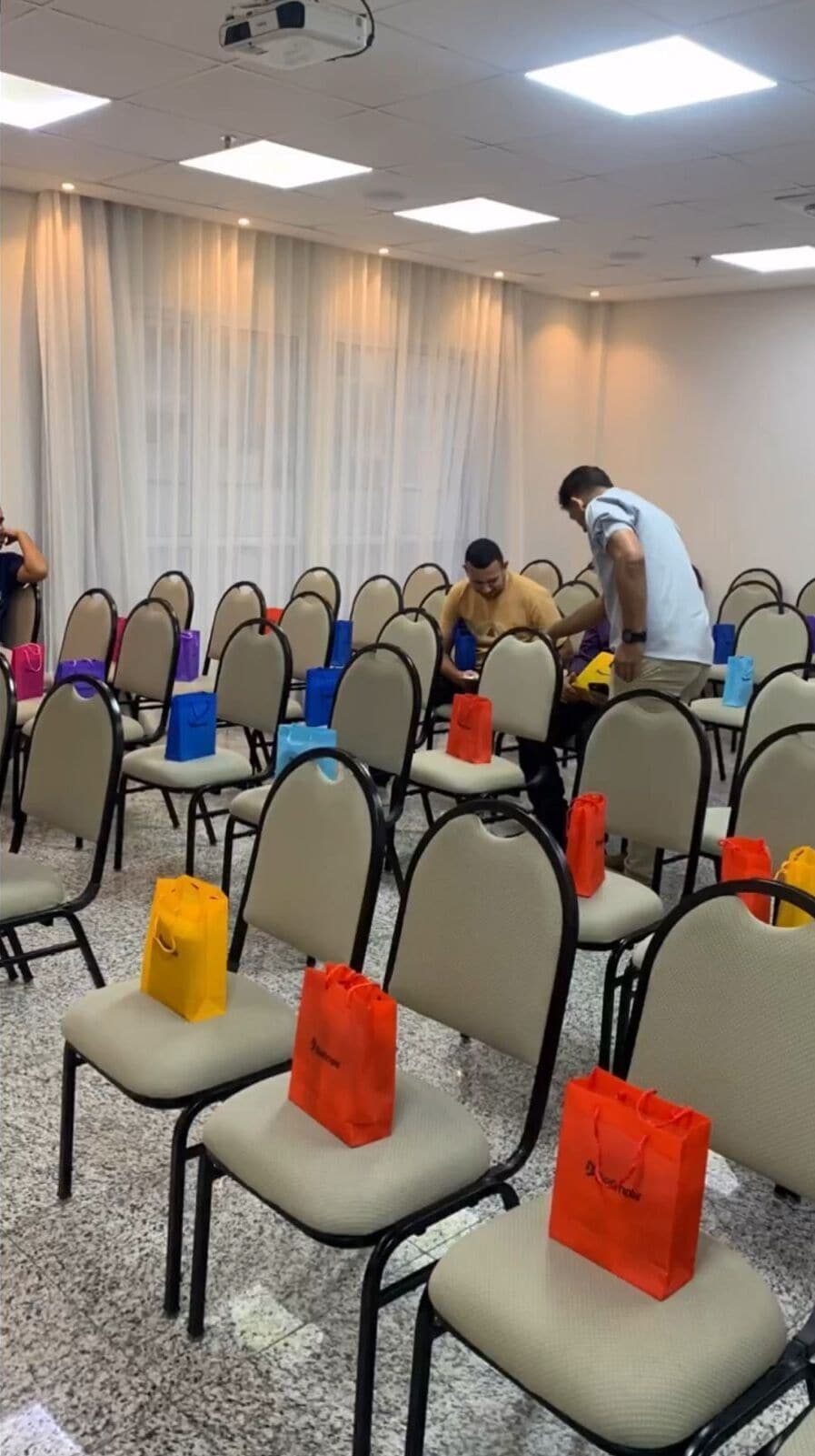 Un salón de conferencias con filas de sillas, algunas con bolsas naranjas.