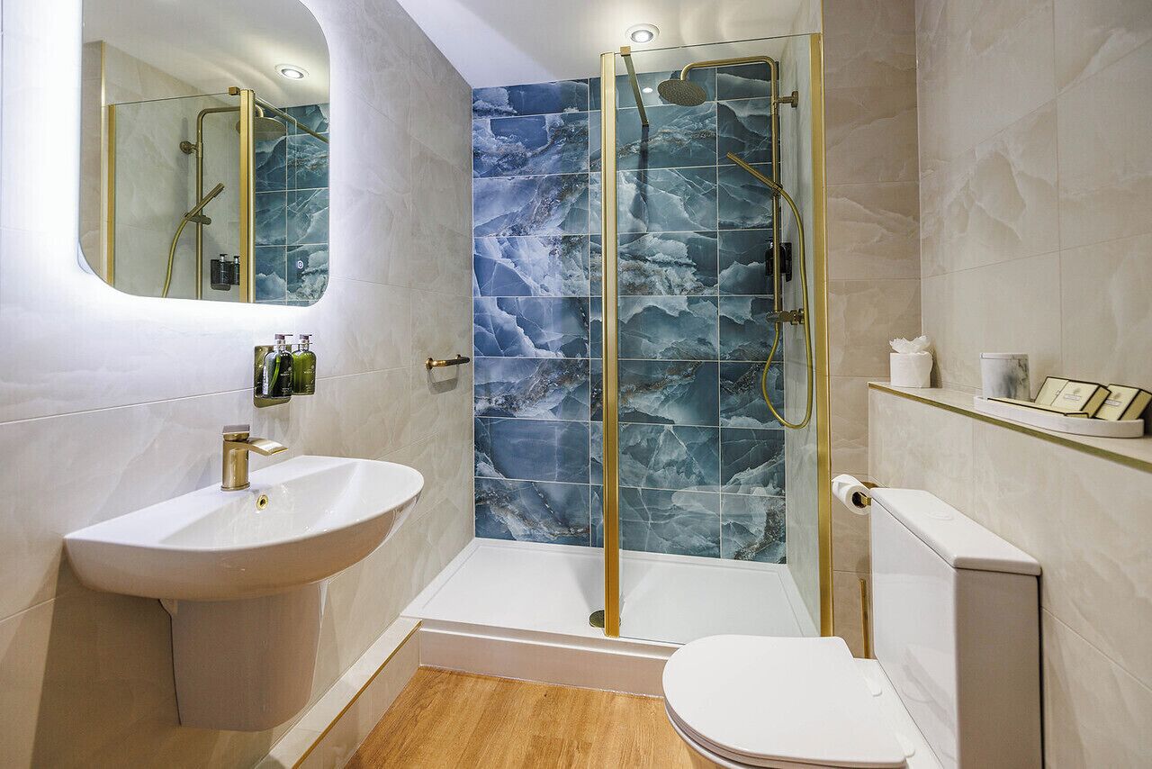 A modern bathroom with a glass-enclosed shower, a pedestal sink, and a toilet.