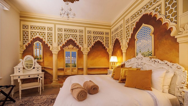 Una habitación de hotel con una cama grande, decoraciones ornamentales en la pared y un candelabro.