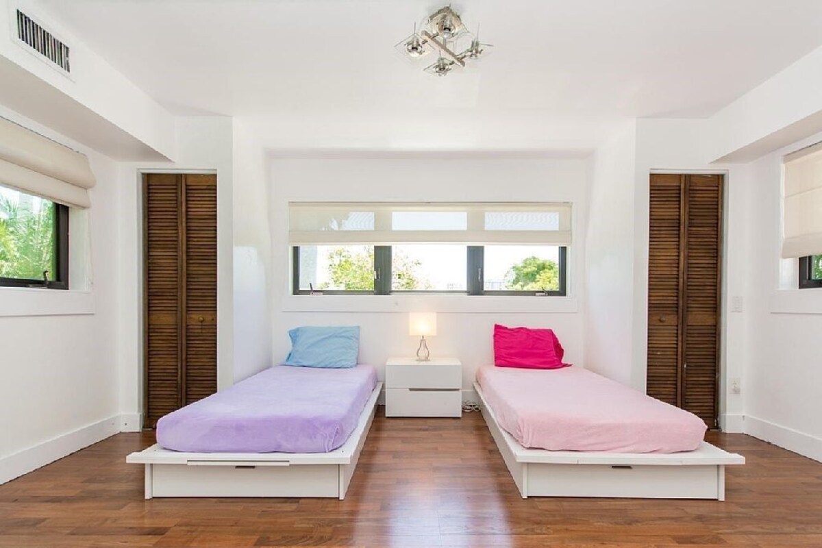 A room with two beds, a window, and a ceiling fan.