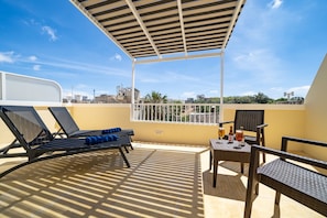 Enjoy a casual dining experience with a city view from this outdoor seating area, featuring lounge chairs and a dining table.