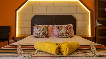 Habitación de hotel con cabecera de ladrillo, dos almohadas y dos toallas enrolladas sobre la cama.