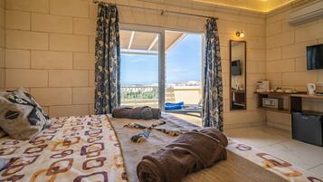 A hotel room with a bed, a bathroom, and a balcony with a view.