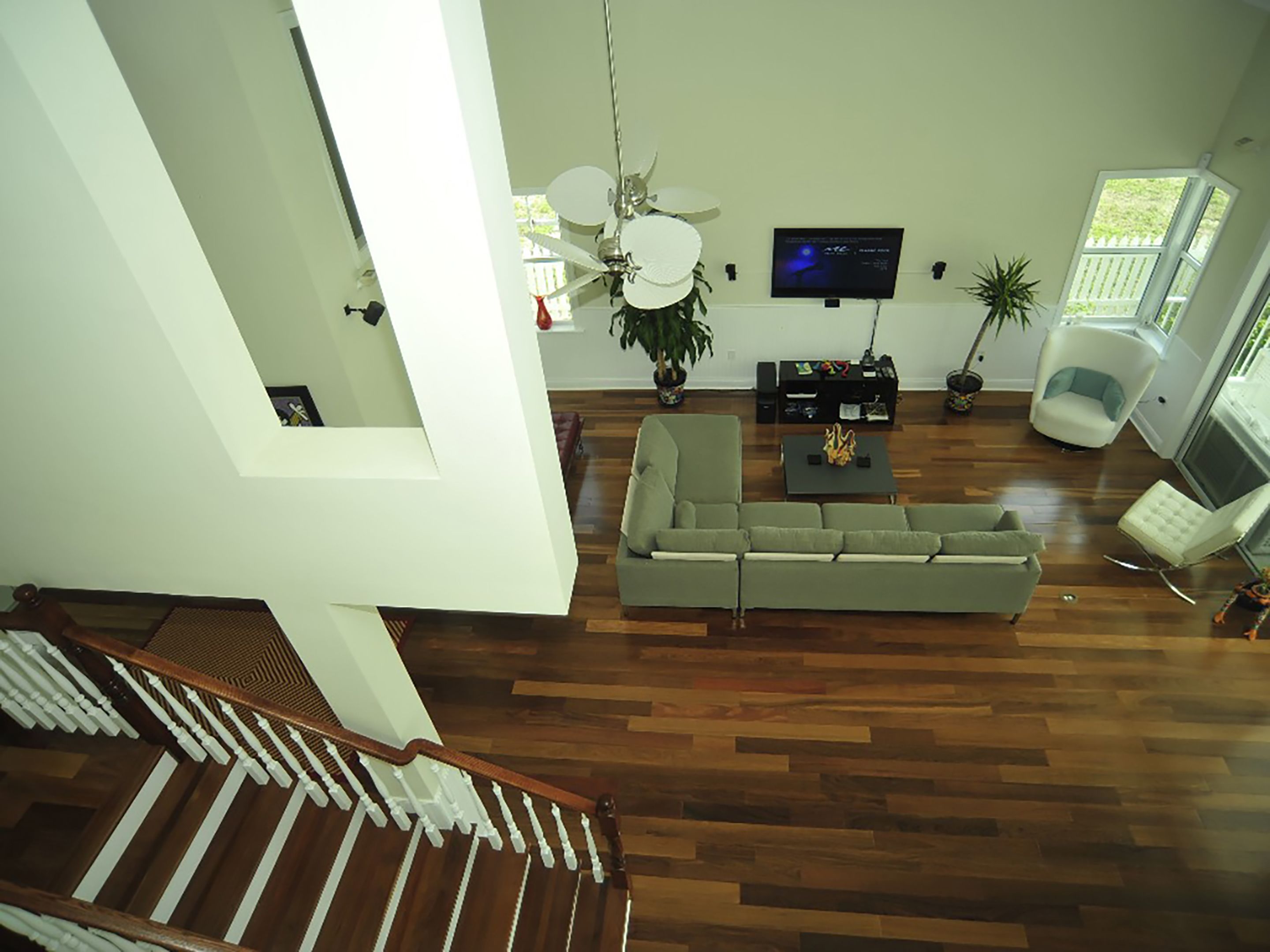 Un salon spacieux avec un grand canapé, une table basse et un téléviseur. Un escalier mène à un autre niveau.