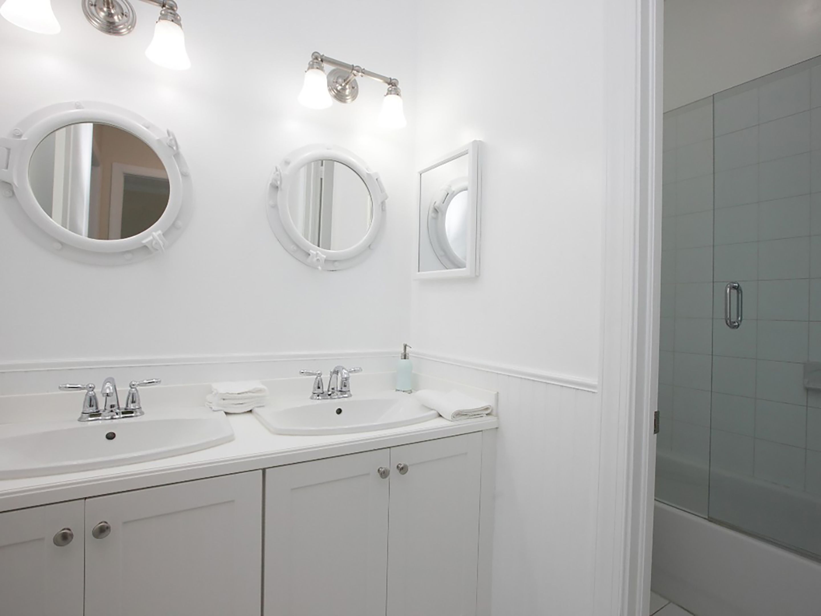 Une salle de bain moderne avec deux lavabos, un miroir et une douche.