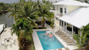 A pool with lounge chairs and inflatable toys, surrounded by palm trees and a waterfront view. - 5 Bedroom Homes in Miami by TMG (Miami)