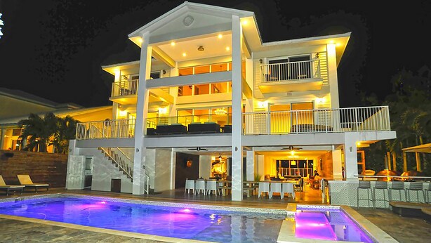 A multi-story hotel with a pool, outdoor seating, and a well-lit balcony area. - 6 Bedroom Homes in Miami by TMG (Miami)