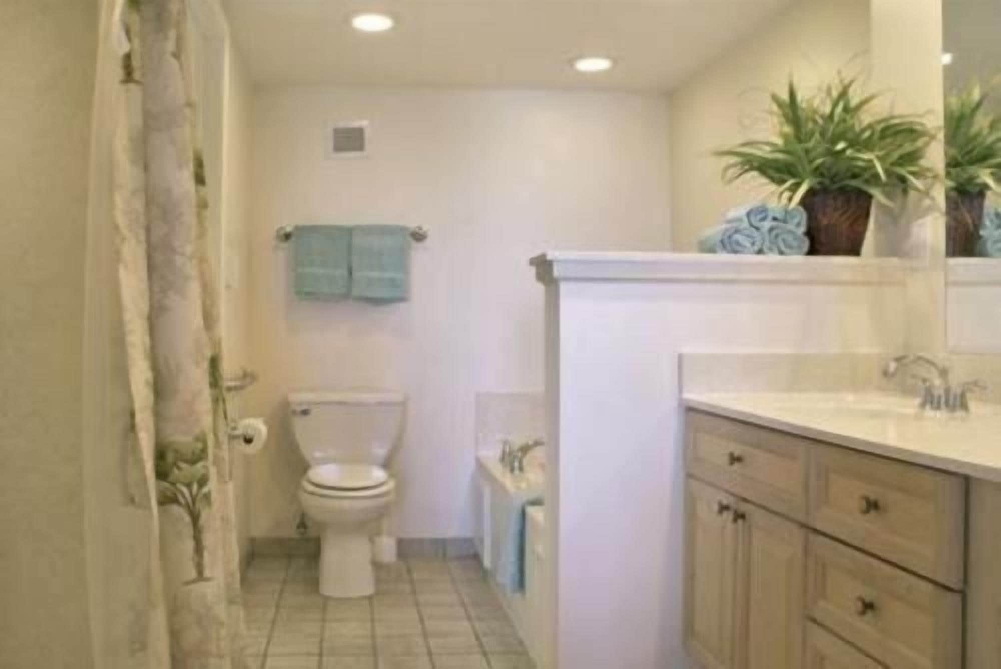 A bathroom with a toilet, sink, and cabinets.