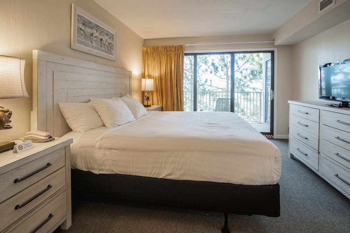 Une chambre d’hôtel avec un grand lit, une télévision, un bureau avec une lampe et une vue sur l’extérieur.