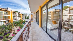 A modern hotel balcony with a view of other buildings, a wooden railing, and potted plants. - Trendy 2BR condo centermost by Happy Address (Playa del Carmen)