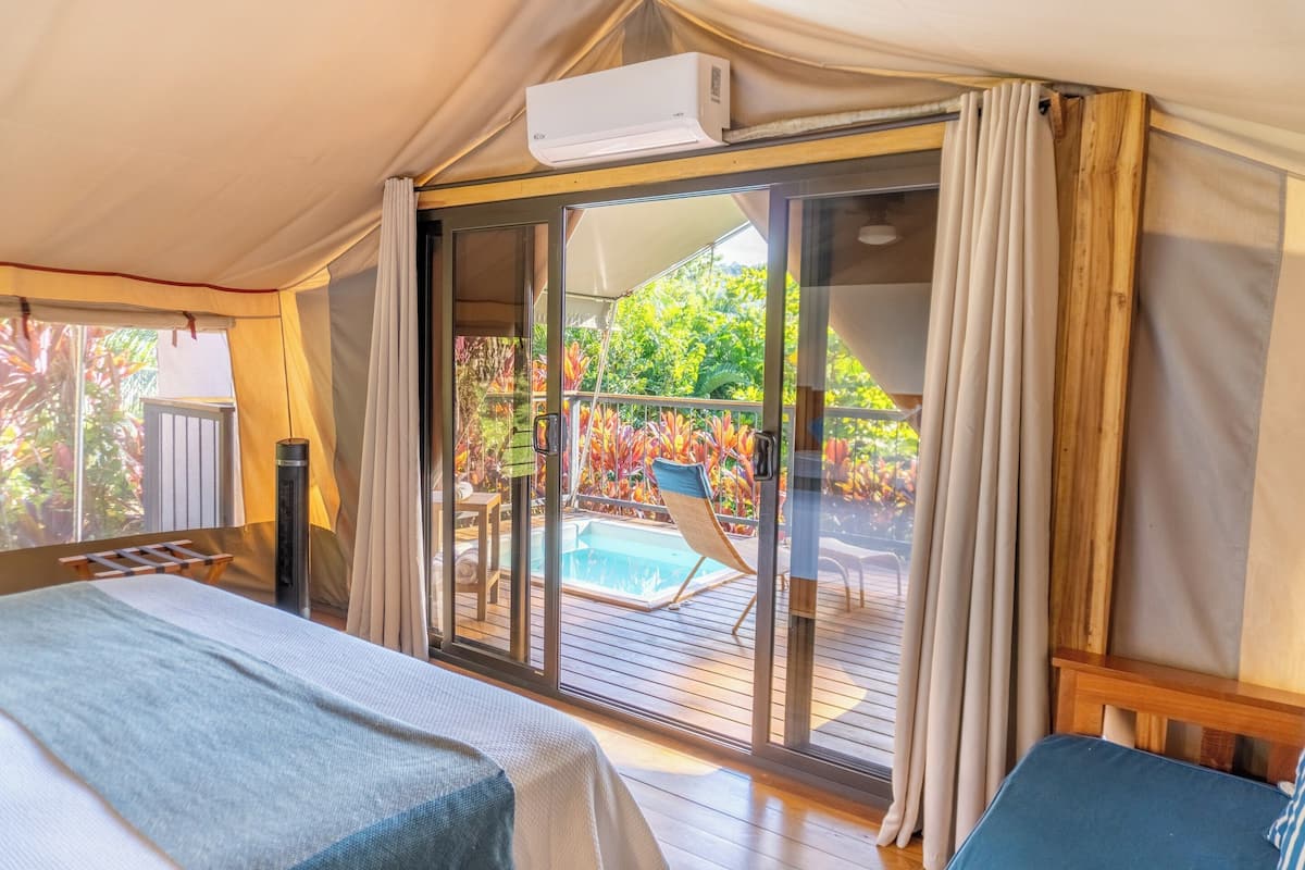 A room with a bed, a sliding glass door to an outdoor pool area, and an air conditioning unit.