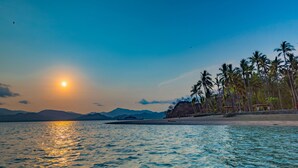 A beach with palm trees and a sunset over the water. - Isla Chiquita Glamping Hotel (Paquera)