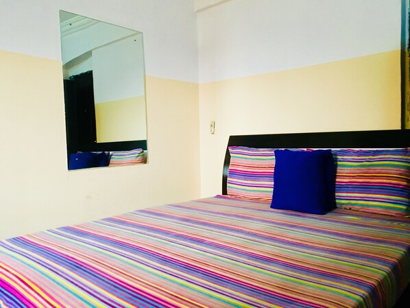 A room with a bed, a mirror, and a wall socket.