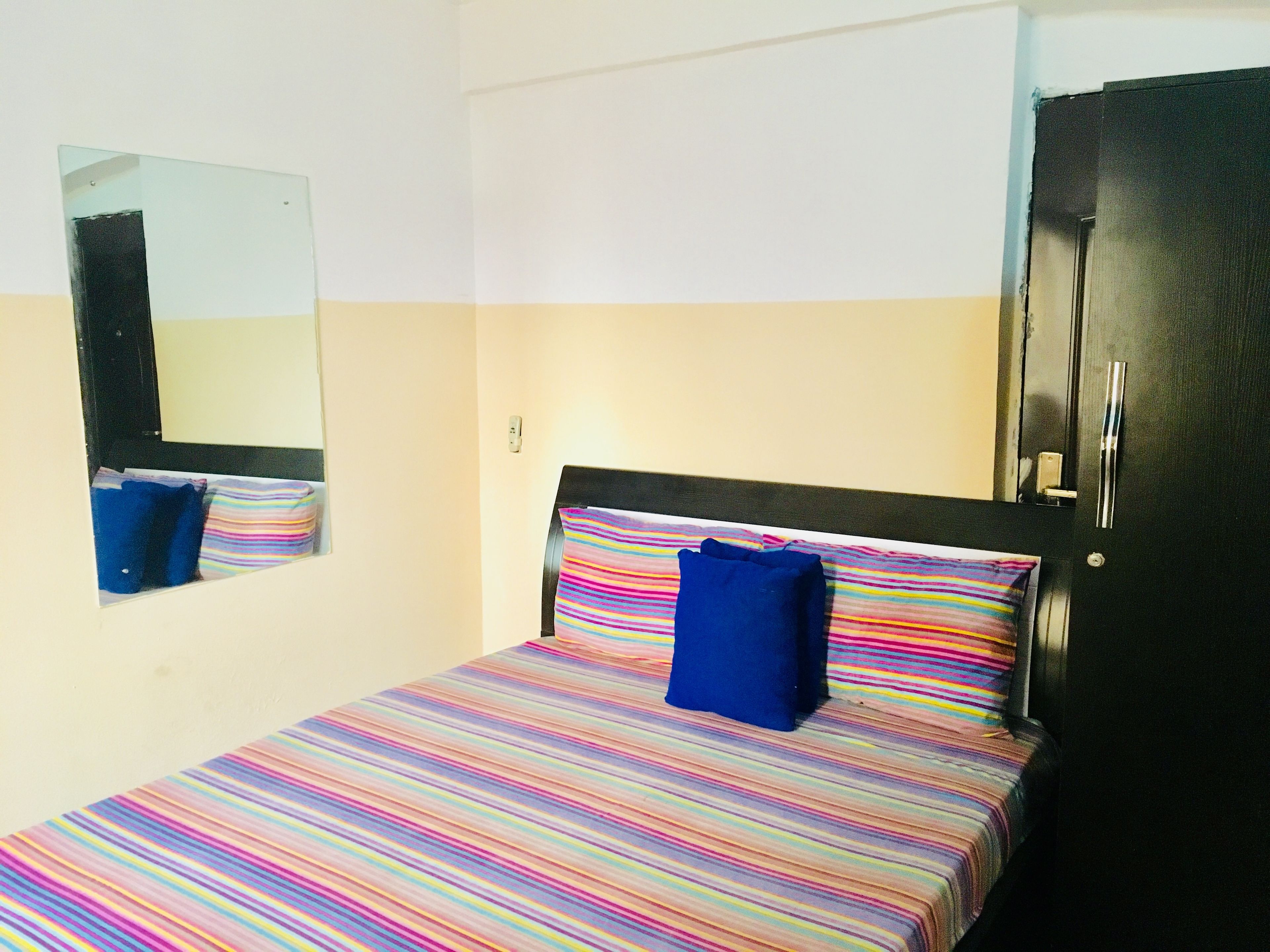 A room with a bed, a mirror, and a door.