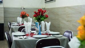 A dining area with tables set for a meal, featuring red roses and white napkins. - Dilic Hotel (Abuja)