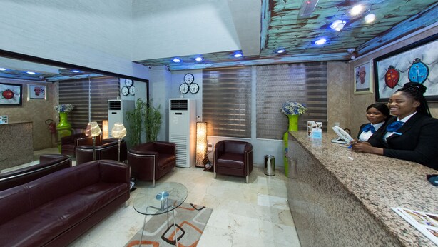 A hotel lobby with a reception desk, leather sofas, a glass coffee table, and decorative plants. - Dilic Hotel (Abuja)