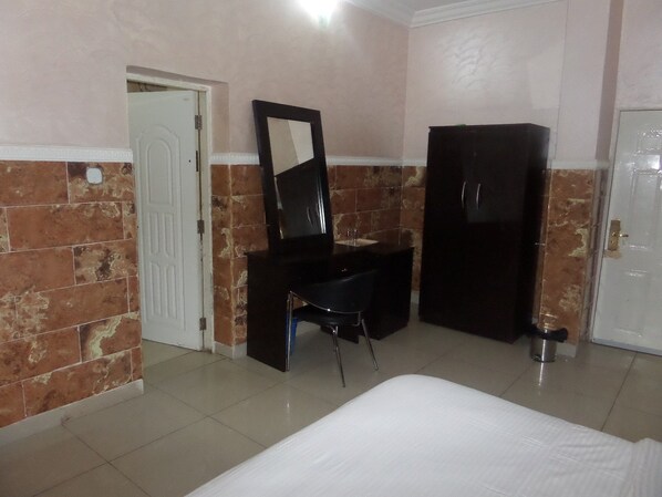 A room with a bed, a desk, a mirror, and a wardrobe.