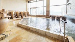 A large indoor pool with clear water, surrounded by stone tiles and a few lounge chairs. - Amanohashidate Hotel (Miyazu)