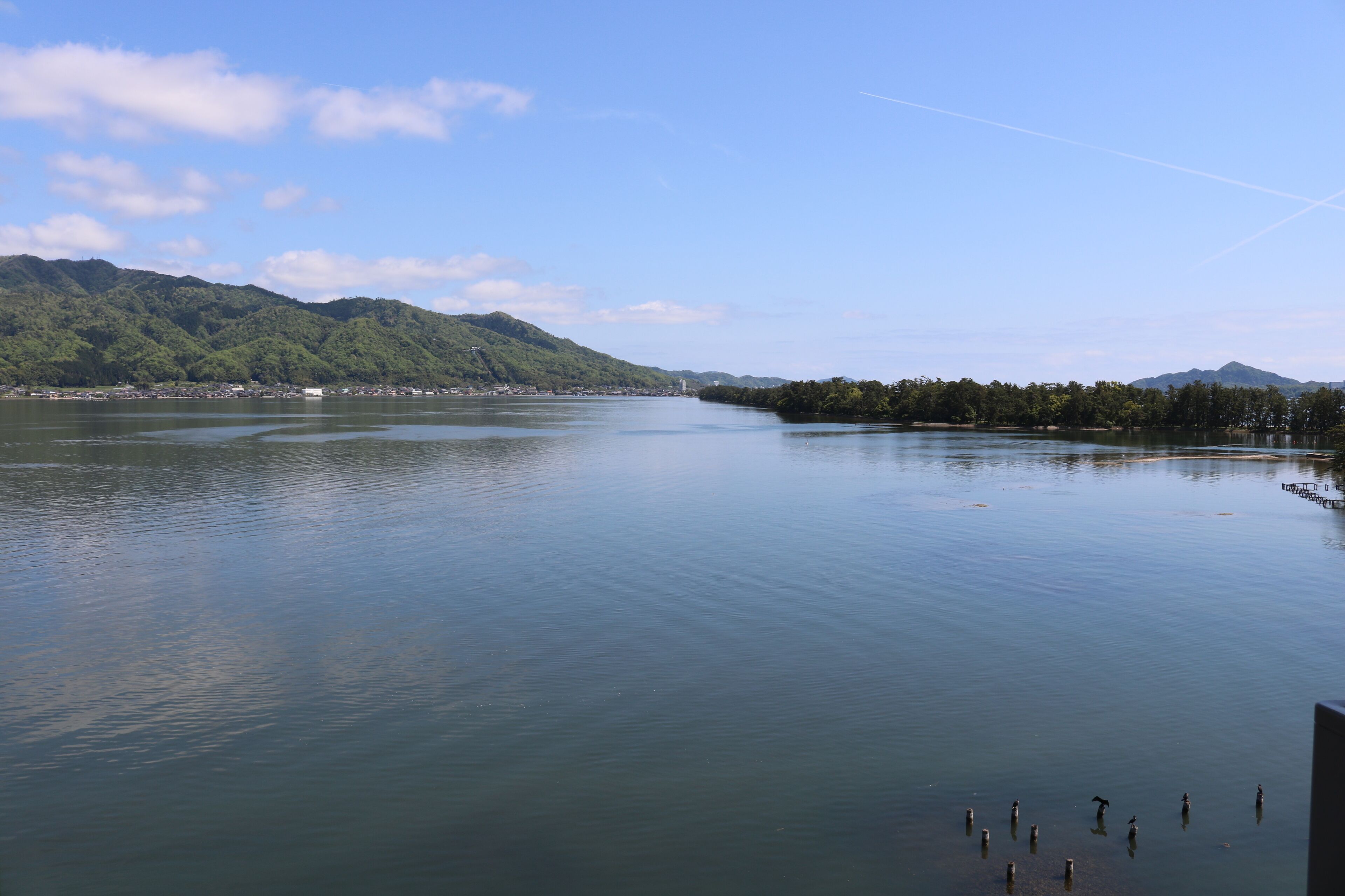 A calm lake with a forested mountain in the background.