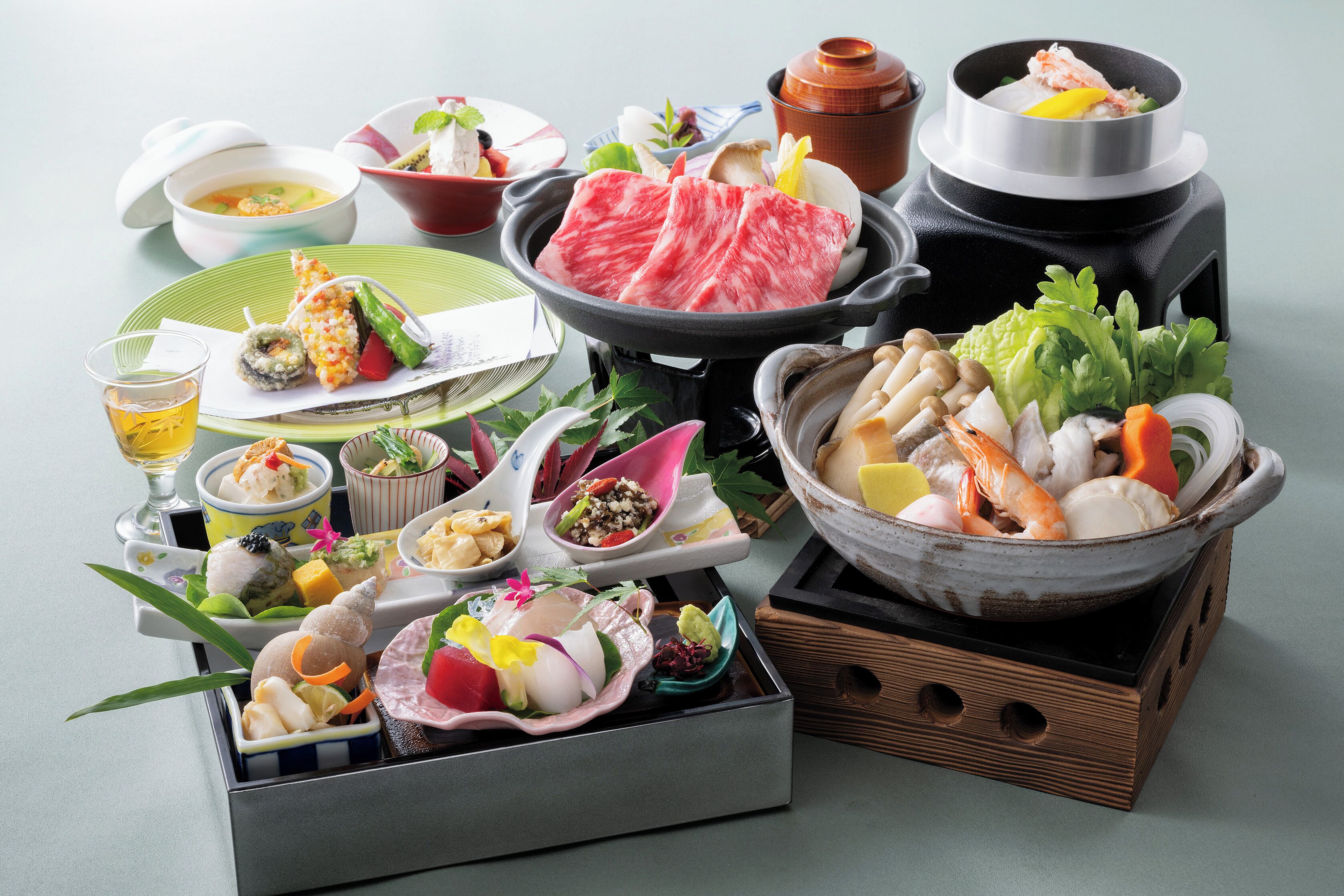 A variety of Japanese dishes including sushi, sashimi, and a hot pot setup.