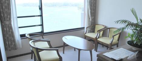 A room with a large window, two chairs, a table, and a potted plant.