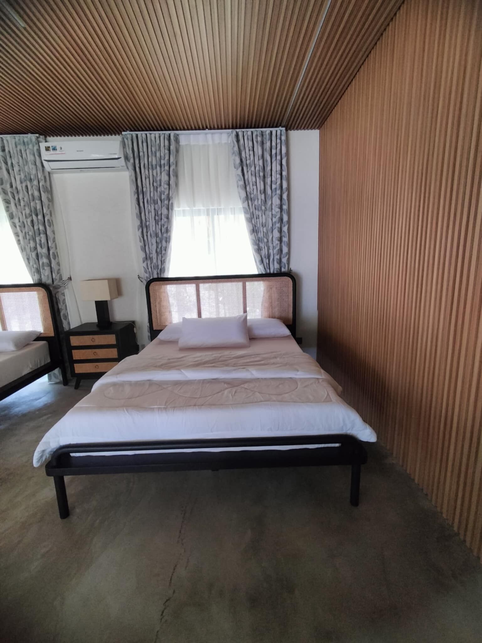 A bedroom with a bed, a nightstand, a lamp, and a window with curtains.