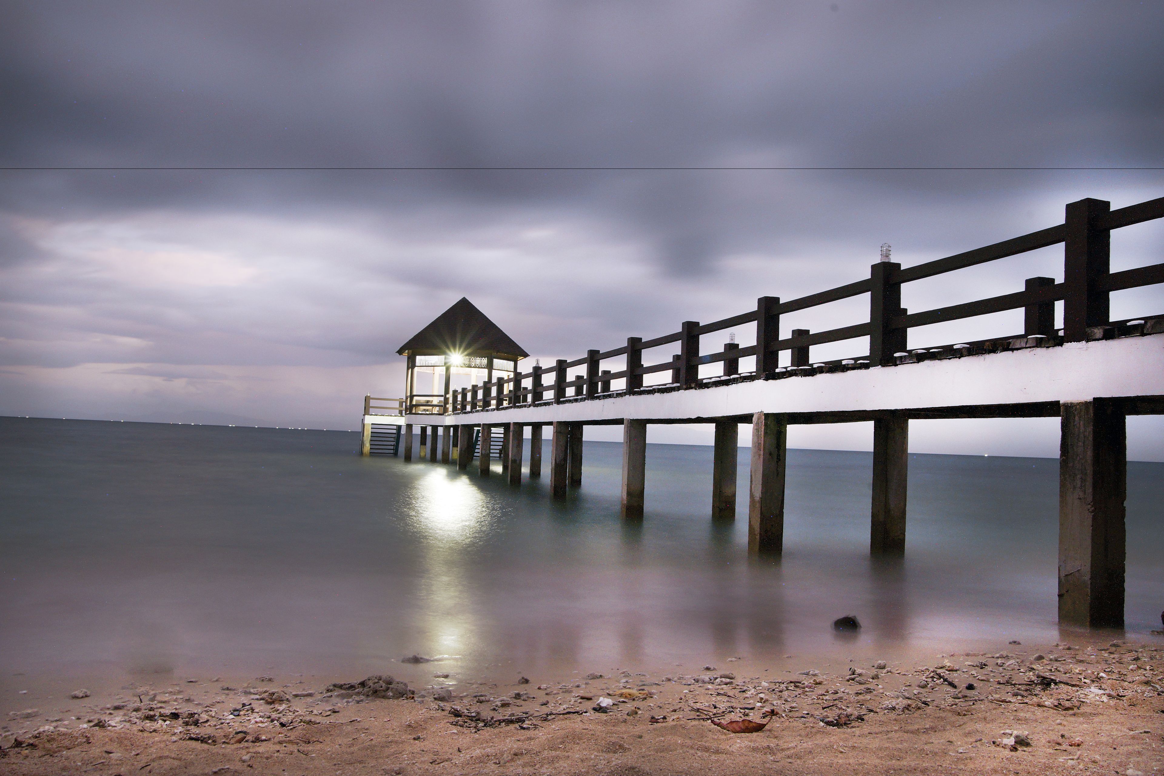 A pier extending into calm waters with a small shelter at the end.