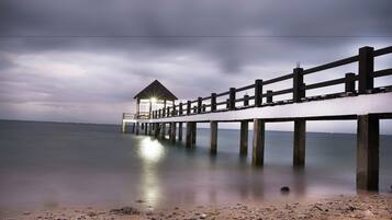 A pier extending into calm waters with a small shelter at the end.