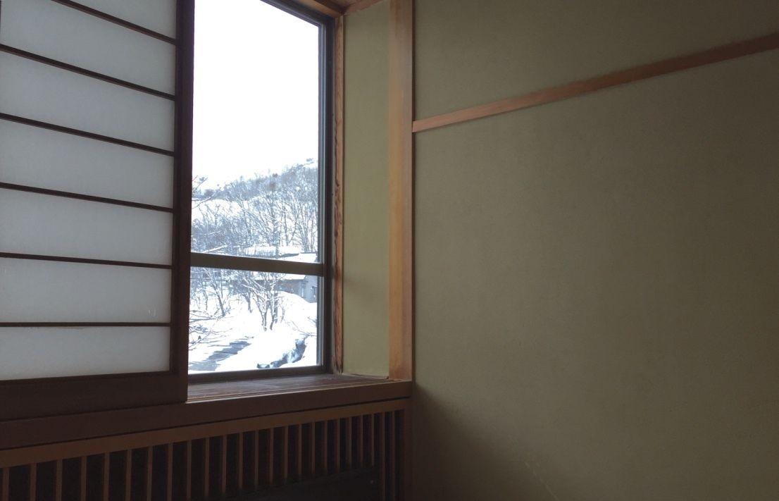 A room with a window overlooking a snowy landscape.