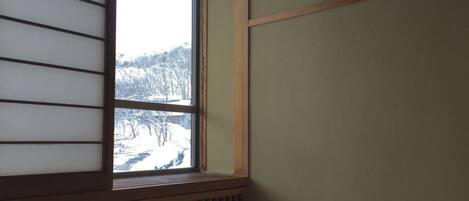 A room with a window overlooking a snowy landscape.