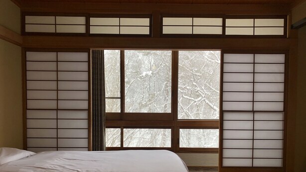 A traditional Japanese-style room with tatami flooring, a futon bed, and shoji screens. - Hakuba Landmark Happo Lodge (Hakuba)
