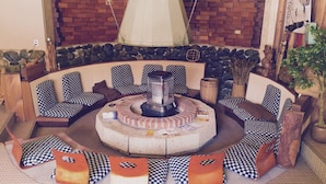 A circular seating area with checkered cushions, a central fire pit, and a brick wall backdrop. - Hakuba Landmark Happo Lodge (Hakuba)