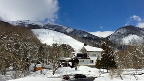 A snow-covered landscape with a house and mountains in the background. - Hakuba Landmark Happo Lodge (Hakuba)