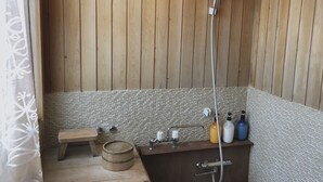 A wooden-paneled shower area with a bench, a wooden barrel, and a sink with toiletries. - Hakuba Landmark Happo Lodge (Hakuba)