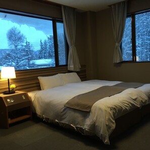 A hotel room with a bed, nightstand, lamp, and curtains. - Hakuba Landmark Iwatake Lodge (Hakuba)
