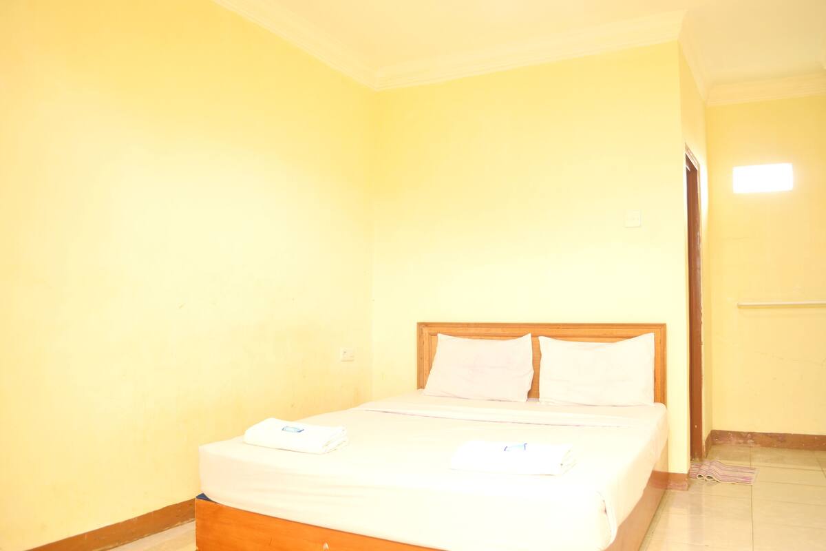 Una habitación con cama, una puerta y una lámpara.