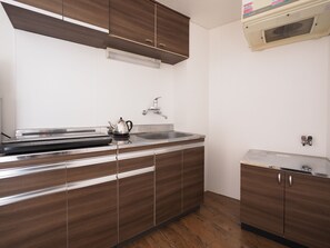 A modern kitchen with wooden cabinets, a stainless steel sink, and a built-in range hood. - Living CUBE Tabata Station (Tokyo)