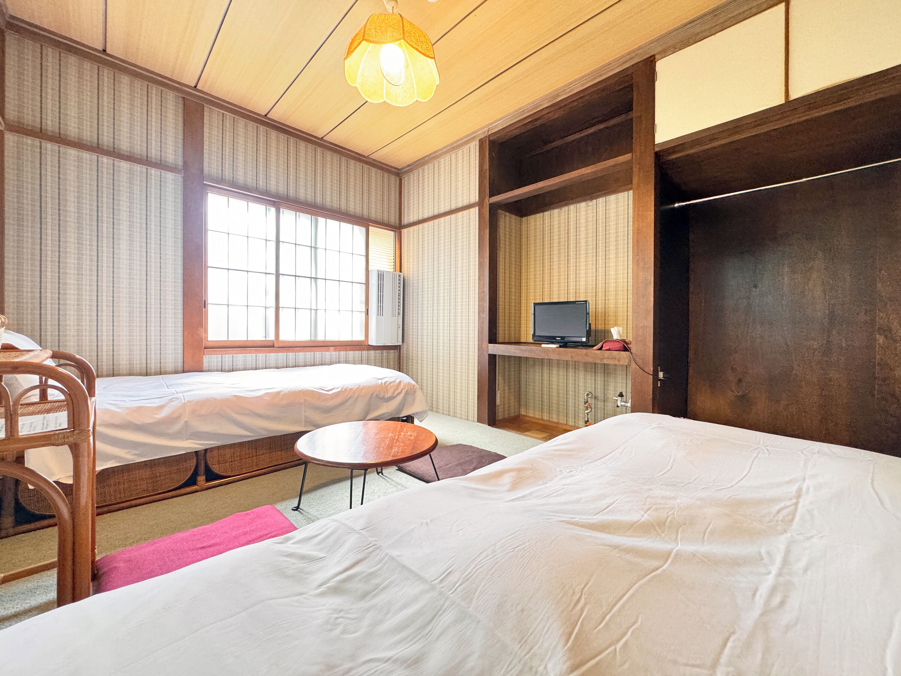 Una habitación tradicional japonesa con dos camas, un televisor y una mesita.