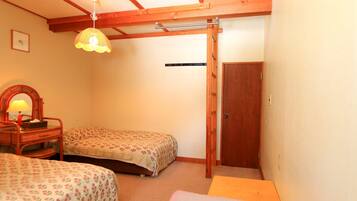 A room with two single beds, a wooden ceiling, a door, and a hanging lamp.