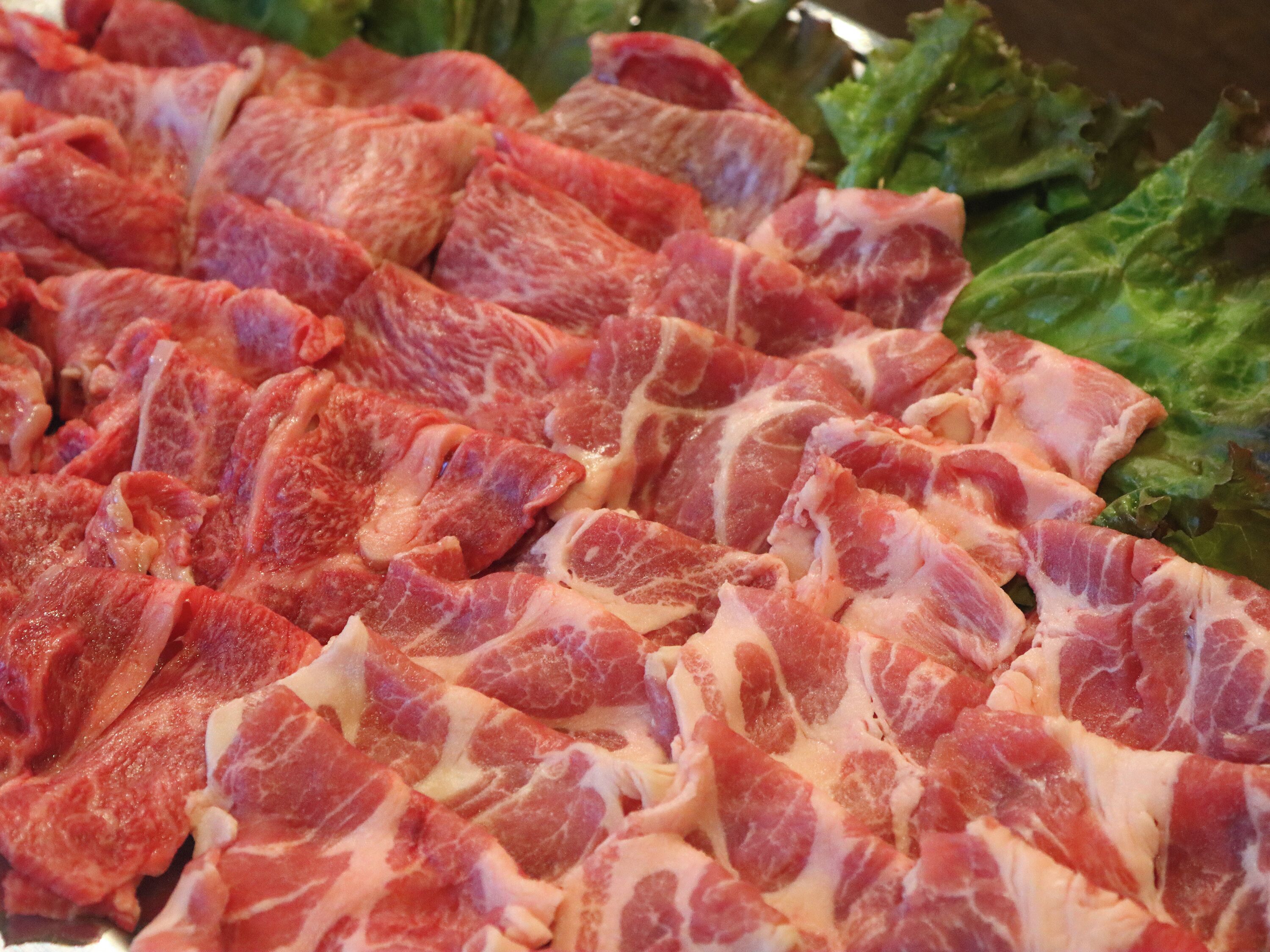 A close-up of raw meat, likely pork, with visible marbling and fat layers.