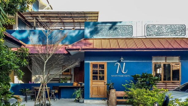 Un hostal con fachada azul, una puerta de madera y un letrero con la letra 'N' en mayúscula.