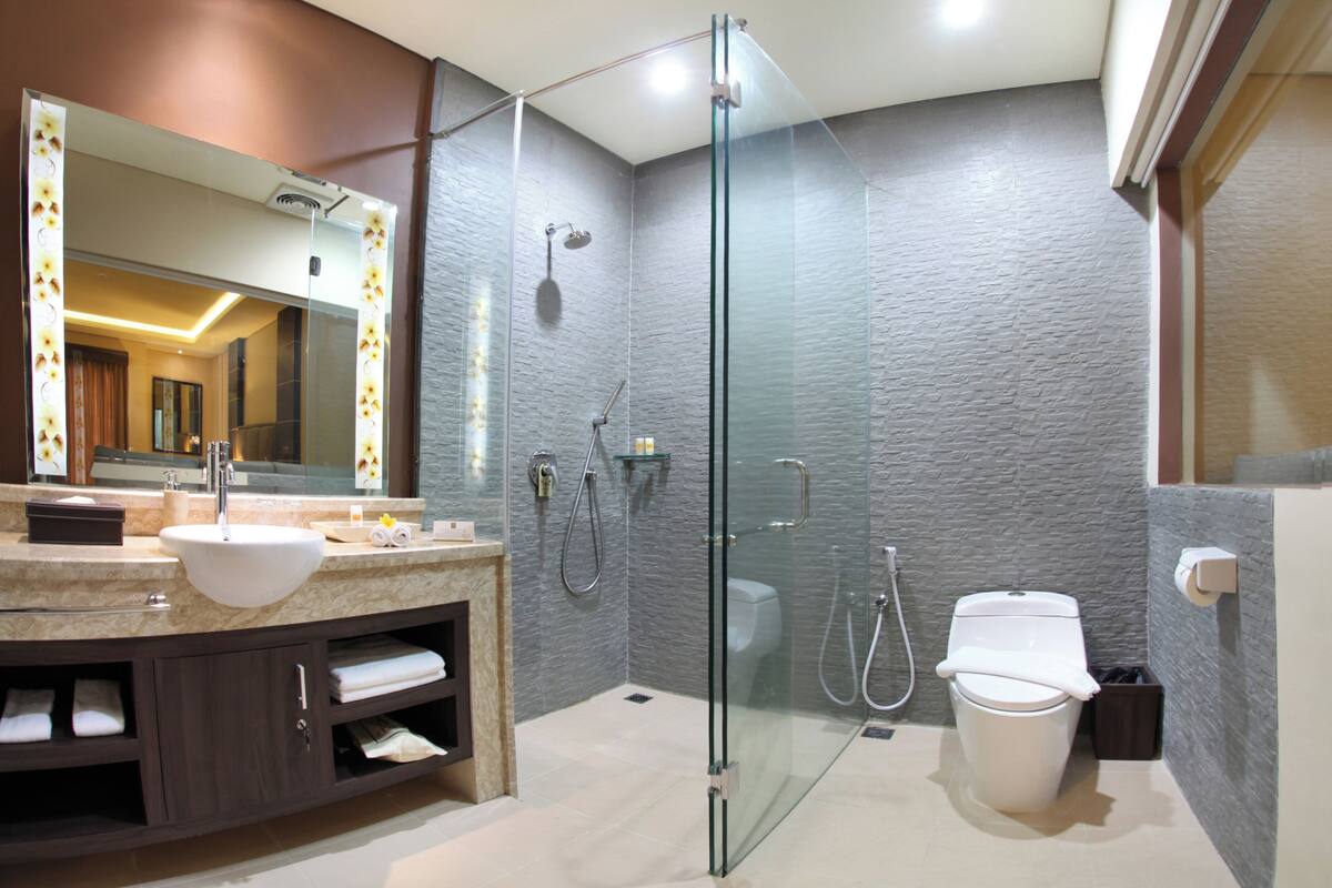 A modern bathroom with a glass-enclosed shower, a white sink, and a toilet.