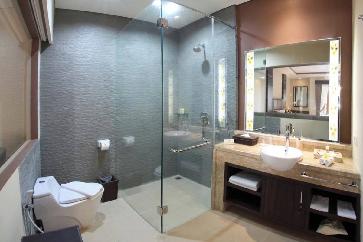 A modern bathroom with a glass-enclosed shower, a white toilet, and a vanity with a large mirror.